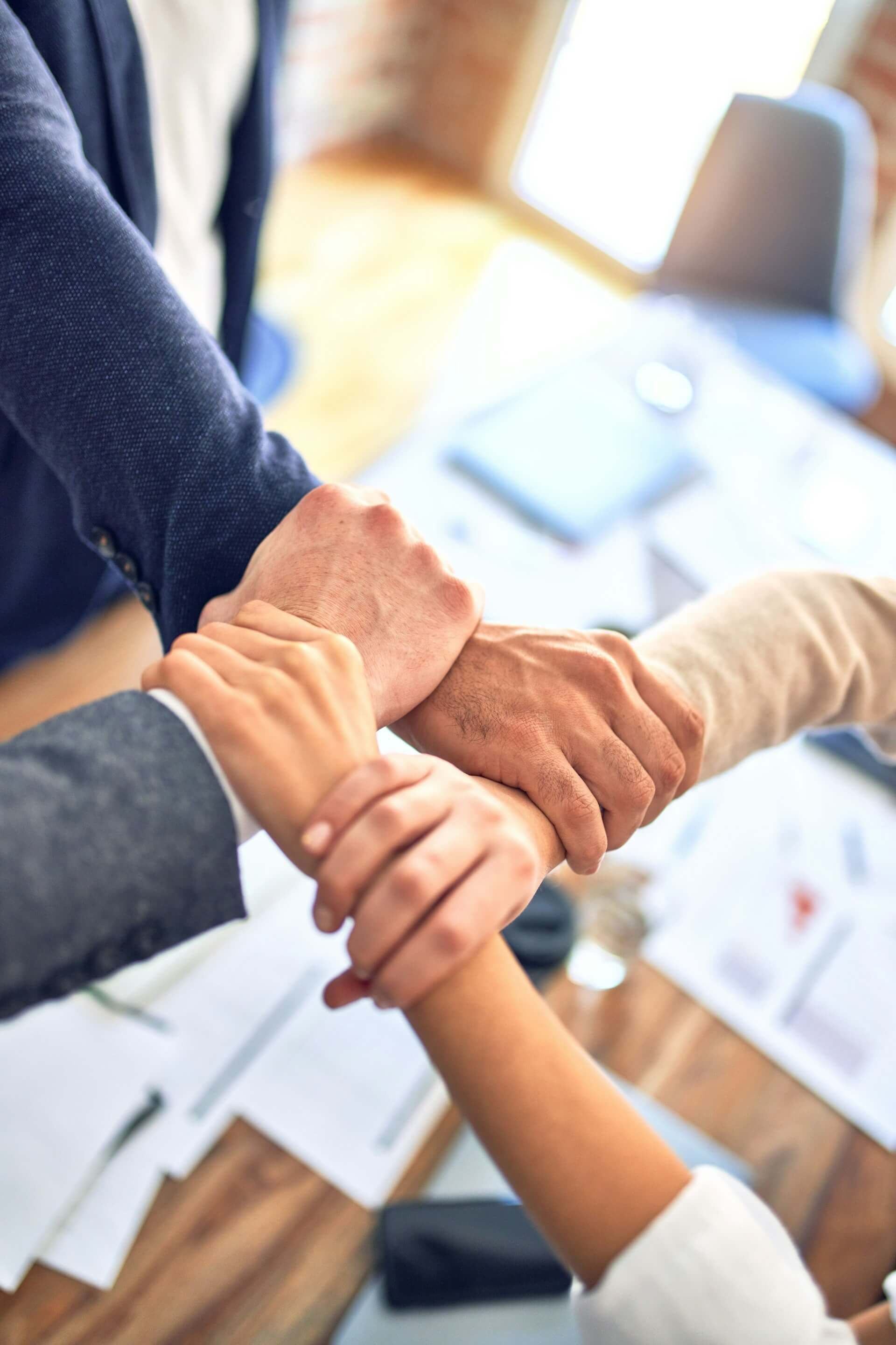 Multiple diverse hands stacked together symbolizing unity and collaborative team effort.